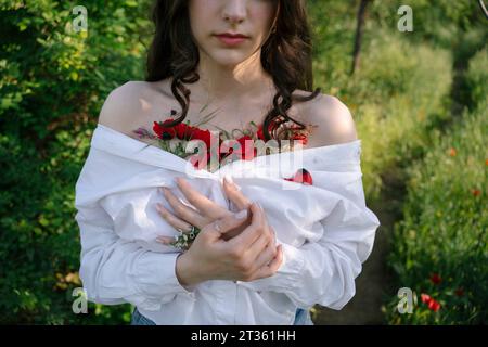 Junge Frau mit Mohnblumen in weißem Hemd Stockfoto