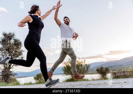 Pärchen geben High-5 und laufen auf Fußweg Stockfoto