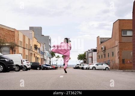 Fröhliche Frau, die unter dem Himmel auf der Straße springt und läuft Stockfoto