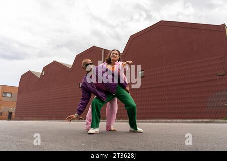 Glückliche Frau, die mit einem Freund vor dem Gebäude tanzt Stockfoto