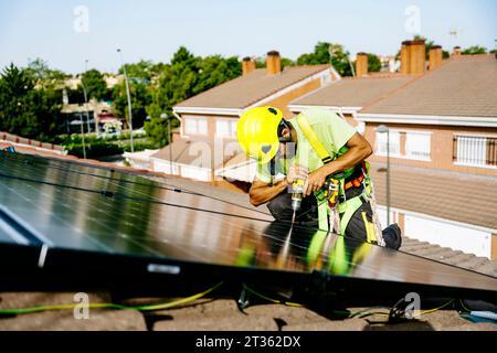 Ingenieur trägt einen Schutzhelm, der den Sonnenkollektor auf dem Dach installiert Stockfoto