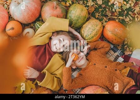 Lächelnde Freunde, die Spaß auf der Decke im Garten haben Stockfoto