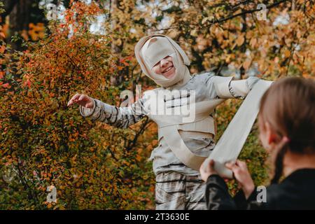 Ein Mädchen, das eine Freundin im Kostüm für halloween im Garten unterstützt Stockfoto