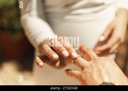 Hand der Braut, die den Ehering an den Finger des Bräutigams legt Stockfoto