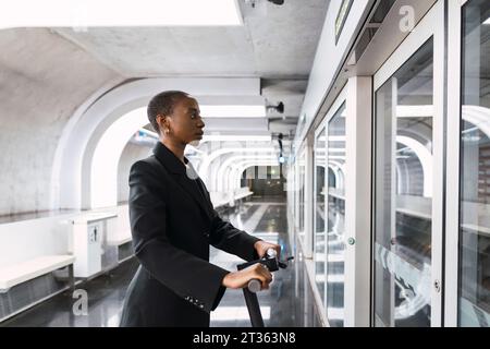 Pendler mit elektrischem Roller und Blick auf den Fahrplan der U-Bahn Stockfoto