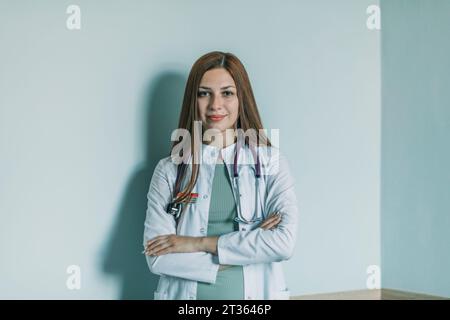 Ärztin mit überkreuzten Armen vor der Wand stehend Stockfoto