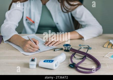 Ärztin schreibt Rezept am Schreibtisch Stockfoto