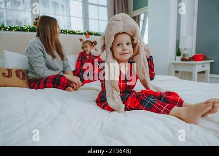 Junge mit Tiermütze, der mit Familie zu Hause auf dem Bett sitzt Stockfoto