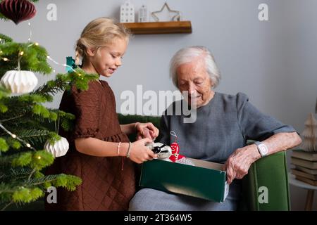 Glückliches Mädchen mit Großmutter, das Weihnachtsschmuck zu Hause wählt Stockfoto