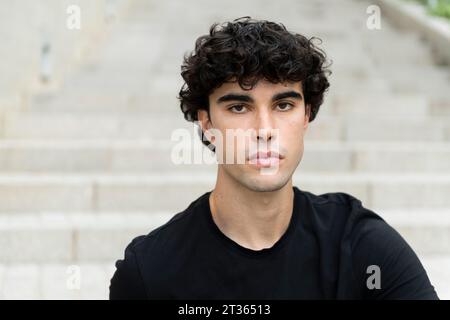 Ernster junger Mann mit schwarzen Haaren Stockfoto