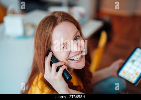 Glückliche Frau am Telefon zu Hause Stockfoto