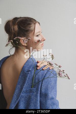 Teenager-Mädchen, das einen Blazer nach hinten trägt, mit Blumen in der Tasche Stockfoto