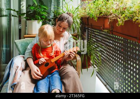 Teenager-Mädchen, das Schwester Ukulele beibringt Stockfoto