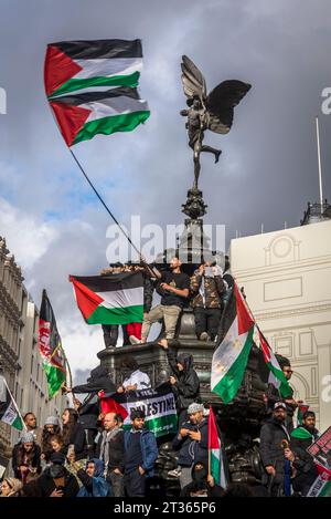 Demonstranten schwingen Fahnen auf der Eros-Statue im Piccadilly Circus, pro-palästinensische Proteste in Zentral-London am 21.10.2023, England, Großbritannien Stockfoto