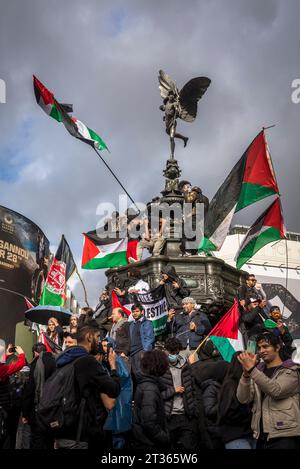 Demonstranten schwingen Fahnen auf der Eros-Statue im Piccadilly Circus, pro-palästinensische Proteste in Zentral-London am 21.10.2023, England, Großbritannien Stockfoto