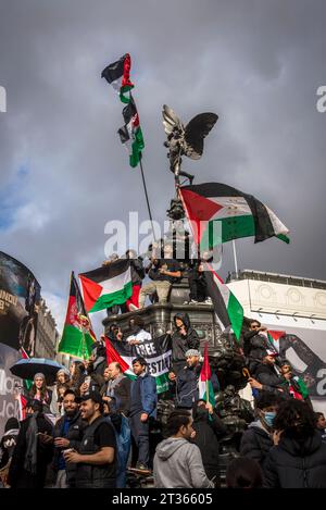 Demonstranten schwingen Fahnen auf der Eros-Statue im Piccadilly Circus, pro-palästinensische Proteste in Zentral-London am 21.10.2023, England, Großbritannien Stockfoto