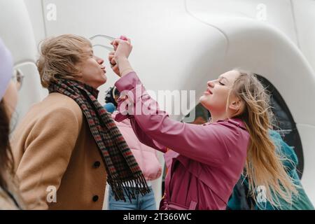 Verspielte Freunde, die Spaß mit einer Sonnenbrille vor dem modernen Gebäude haben Stockfoto