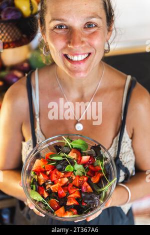 Lächelnde Frau, die Salatschüssel hält Stockfoto