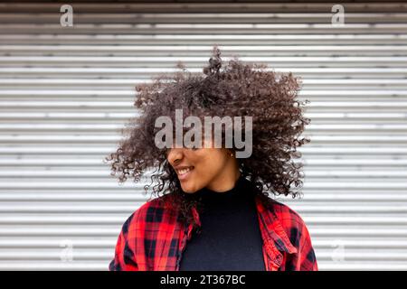 Lächelnde Frau, die Haare vor den Auslöser wirft Stockfoto