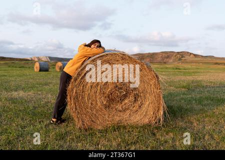 Frau lehnt sich auf dem Feld auf Heu Stockfoto