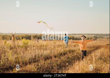 Verspielter Vater und Söhne fliegen Drachen im Feld Stockfoto