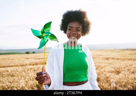 Lächelnde Frau, die grünes Flitzenrad auf dem Feld ansieht Stockfoto