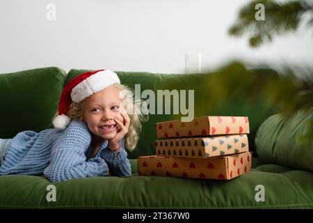 Glückliches Mädchen, das zu Hause in der Nähe von Weihnachtsgeschenken liegt Stockfoto