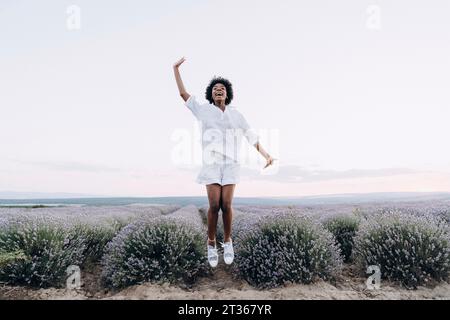 Glückliche Frau, die in die Nähe des Lavendelfeldes springt Stockfoto