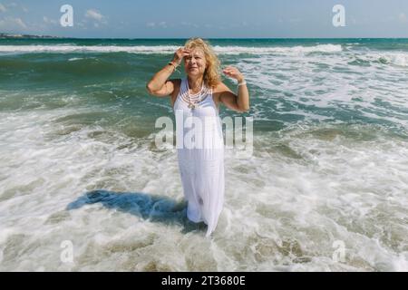 Eine Frau im Kleid, die am Strand steht Stockfoto