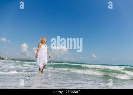 Eine ältere Frau, die am Strand entlang läuft Stockfoto