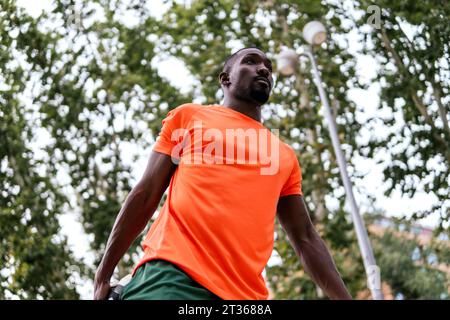 Mann mit orangefarbenem T-Shirt, der im Park trainiert Stockfoto