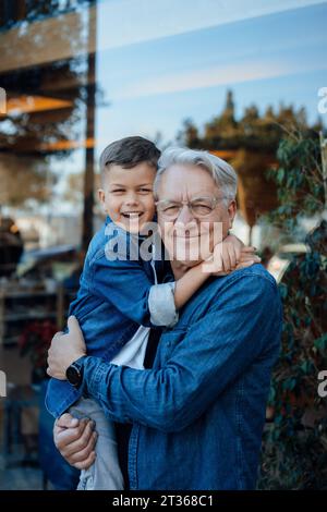 Glücklicher Junge, der einen älteren Mann in der Nähe der Mauer umschließt Stockfoto