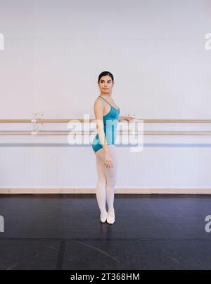 Mädchen in Ballettkostüm, das in der Tanzschule neben Geländer steht Stockfoto
