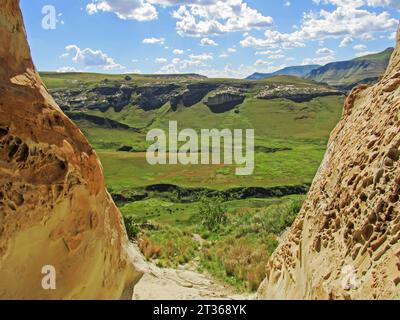 Die grünen alpinen Graslandschaften des Golden Gate Highlands National Park, gesehen durch die Mündung einer Sandsteinhöhle mit Wabenwitterung Stockfoto