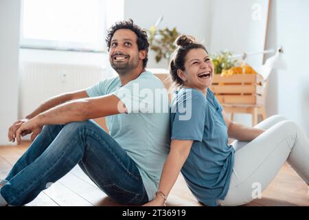 Glückliche Frau und Mann sitzen zu Hause auf dem Boden Stockfoto