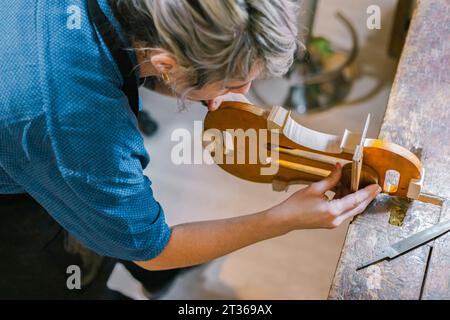 Geigenbauer arbeitet an der Violine am Schreibtisch in der Werkstatt Stockfoto