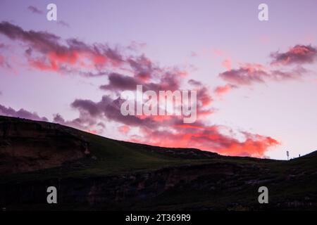 Leuchtend rosa und violette Wolken bilden eine leichte Vogelform im Golden Gate Highlands National Park, Südafrika Stockfoto