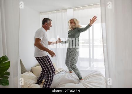 Sorgloses Paar, das zu Hause auf dem Bett tanzt Stockfoto