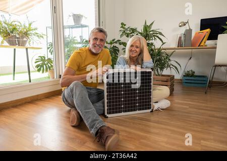 Lächelndes reifes Paar mit Sonnenkollektor zu Hause Stockfoto