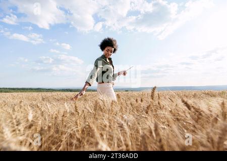 Junger Afro-Agronomist mit Tablet-PC, der Gerste im Feld untersucht Stockfoto