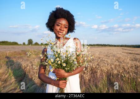 Glückliche junge Frau mit Blumenstrauß auf dem Feld Stockfoto