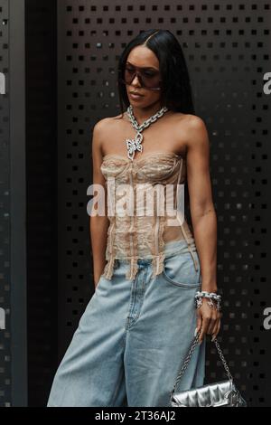 Aleali May trägt eine Sonnenbrille, eine Kette, ein schulterfreies Oberteil mit Rüschen, eine blassblaue, breite Jeans und eine silberne Gucci-Tasche vor der Gucci-Show während M Stockfoto