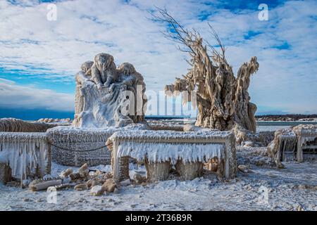 Seltsame Eisformationen auf dem Denkmal, Bäume und Bänke am Pier in Lake Erie, Kanada, Tag nach Wintersturm, stürmischer Himmel Stockfoto