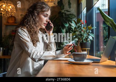 Geschäftsfrau, die im Café am Smartphone spricht Stockfoto