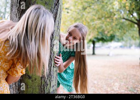 Fröhliche Tochter, die mit Mutter im Park Verstecken spielt Stockfoto