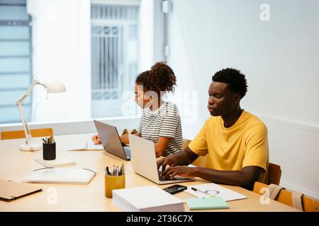 Schüler, die am Schreibtisch lernen und mit einem Laptop arbeiten Stockfoto
