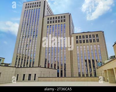 Mehrstöckiges Wohngebäude mit untergehenden Sonnenstrahlen vor blauem Himmel. Modernes mehrstöckiges Wohngebiet Stockfoto