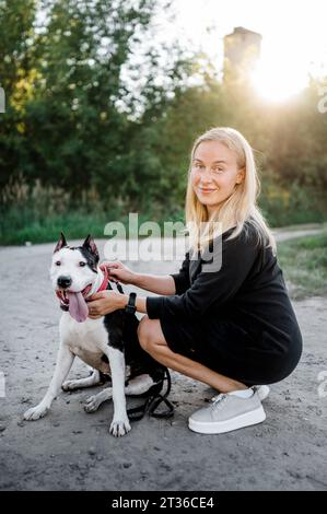 Lächelnde Frau in der Nähe des Hundes im Park Stockfoto