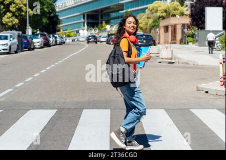 Lächelnder Schüler mit kabellosen Kopfhörern auf der Straße Stockfoto