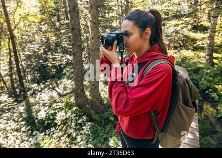 Junge Frau, die mit Kamera im Wald fotografiert Stockfoto